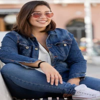 Mujer con chaqueta de mezclilla y gafas de sol sonriente